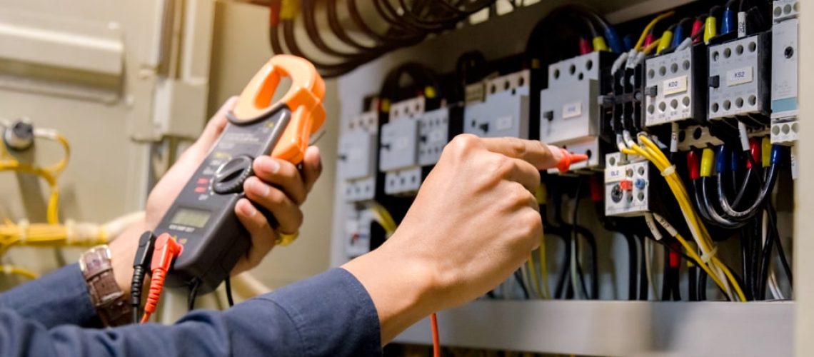 Electrical engineer testing voltage and current levels in an electrical panel, related to commercial energy-saving solutions.