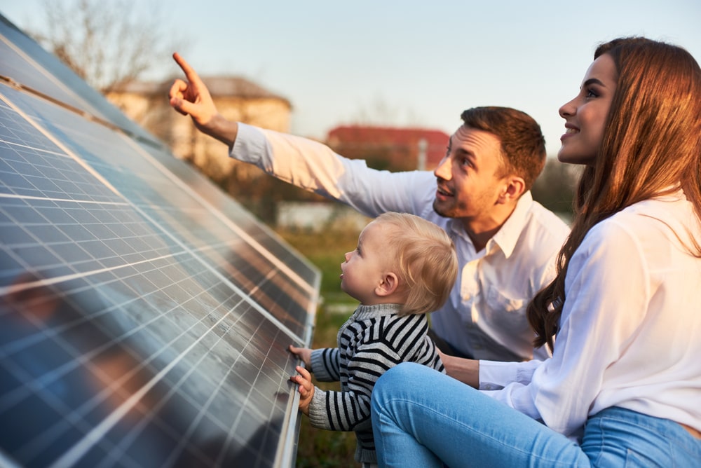 A family examines solar panels near their home, illustrating the growing interest in renewable energy among New Orleans residents.