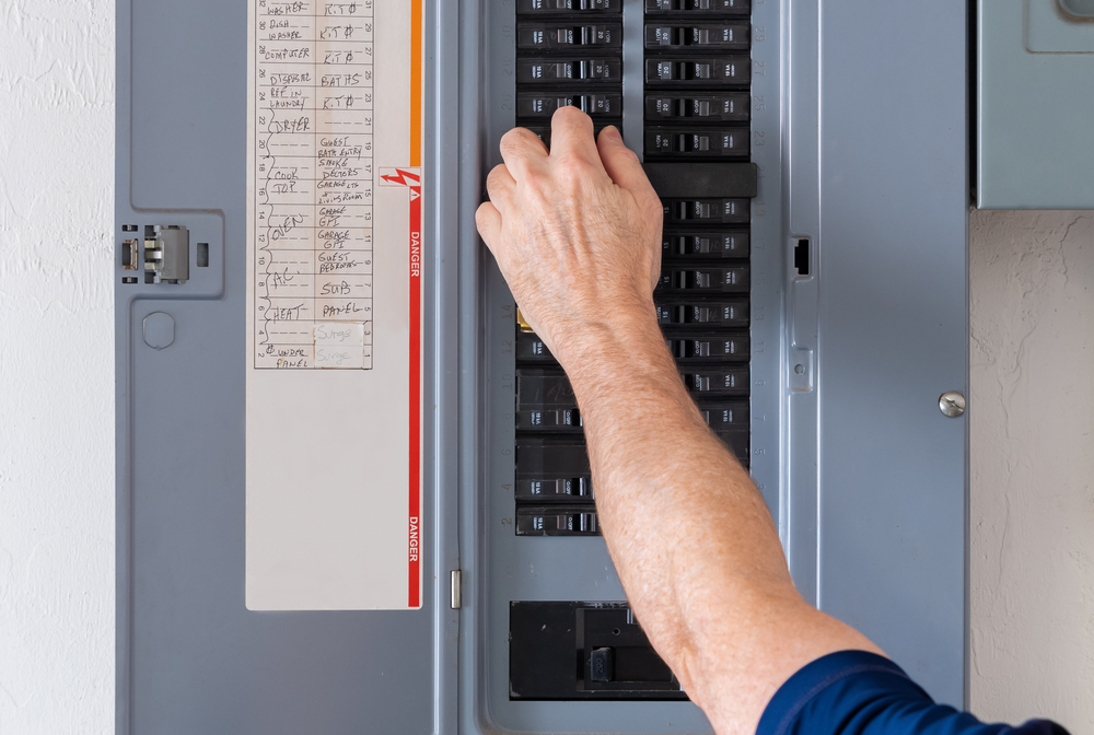 Electrician resetting a tripped circuit breaker in a residential electrical panel, demonstrating expertise in panel maintenance and upgrades.